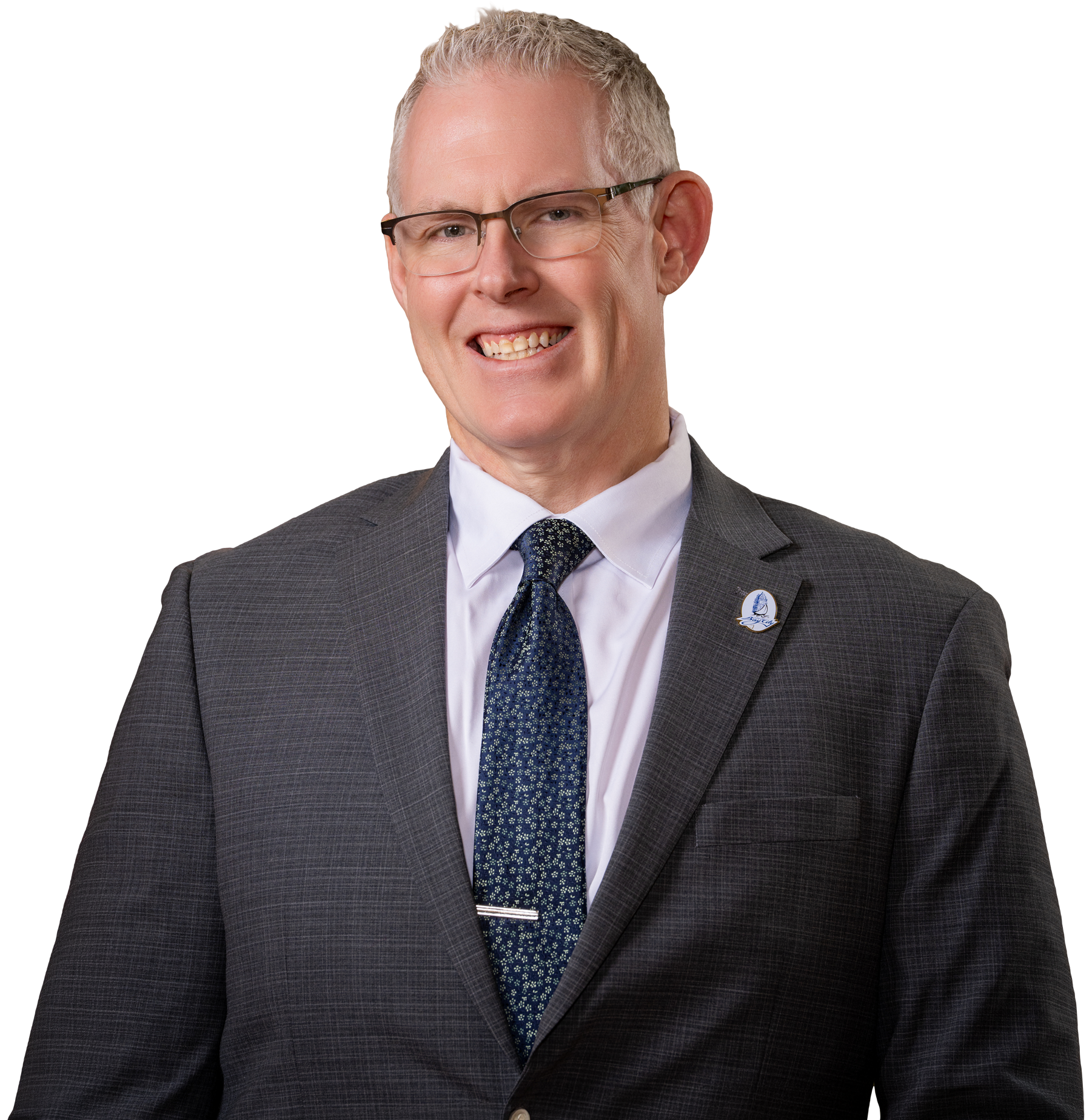 Chris wearing glasses, a gray suit, white shirt, and a blue patterned tie, smiling at the camera.