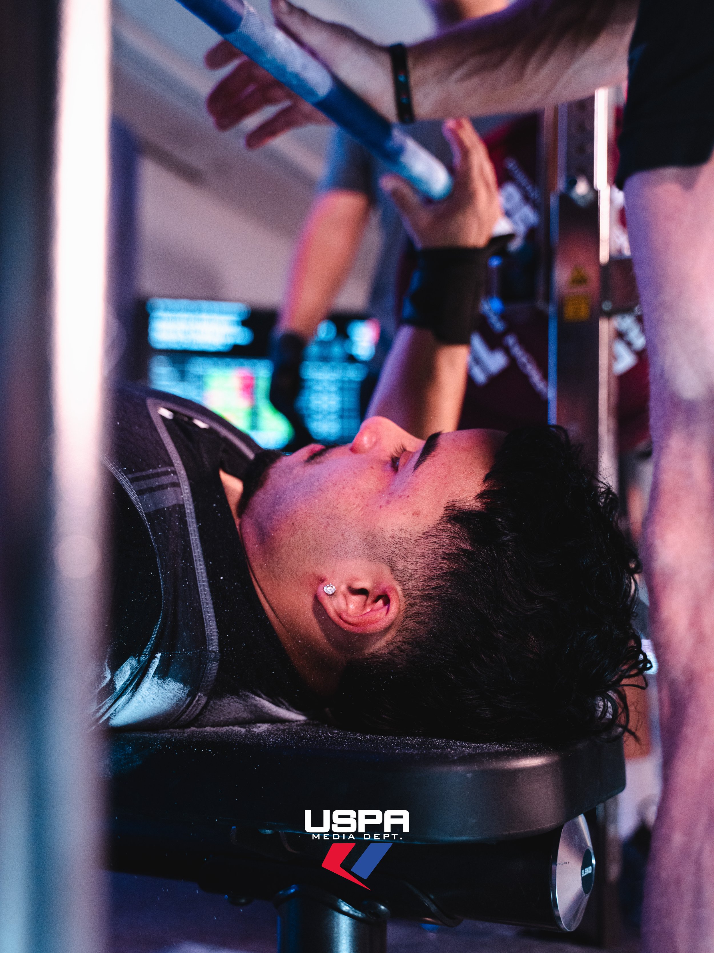 Uplift Grant recipient is laying on a bench while preparing his hand placement for the bench press attempt.