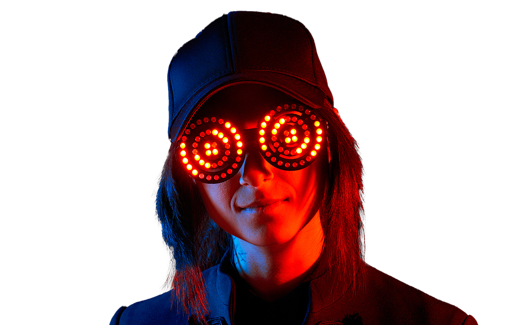 A woman wearing a baseball cap and sunglasses with red LED lights in a spiral pattern, illuminated in dark lighting.