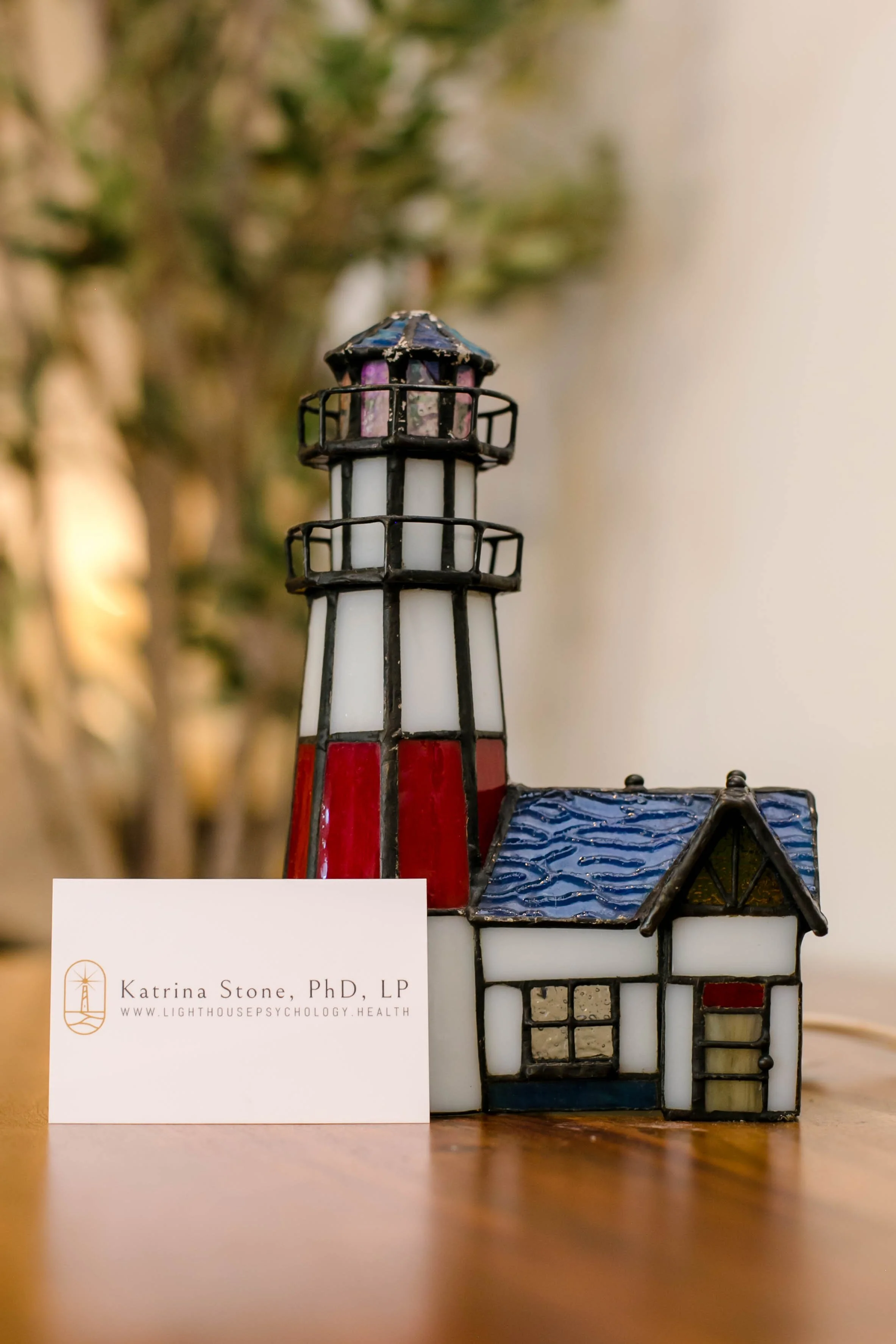 a lighthouse figurine with behind Katrina Stone's business card