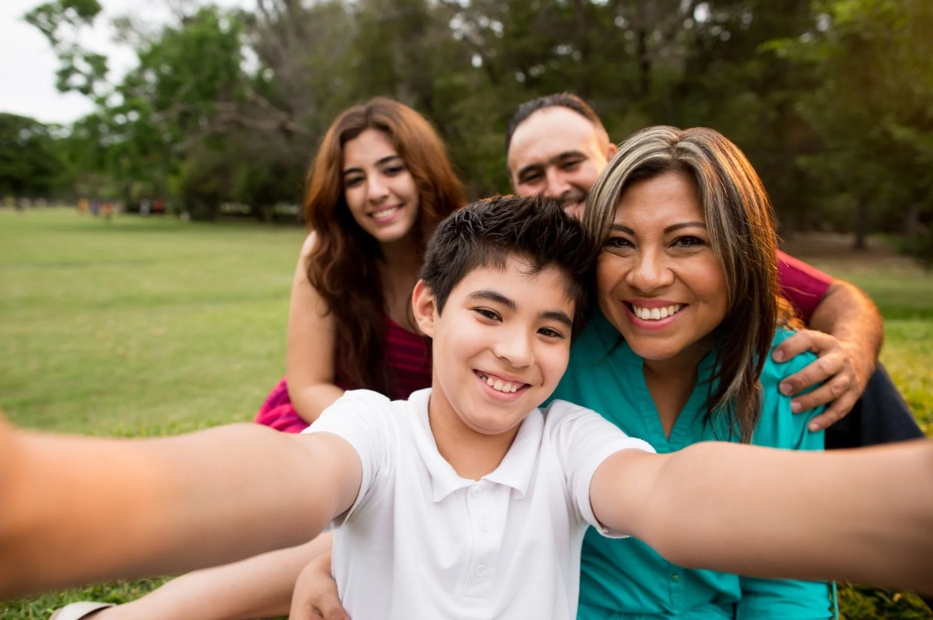 a young boy taking a selfie photo with his mother, father, and sister