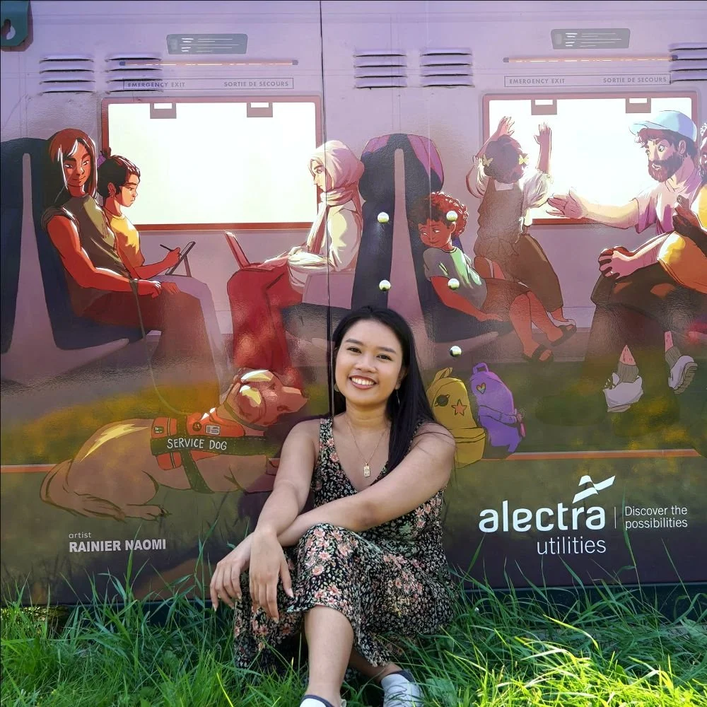 The artist sitting in front of her mural box