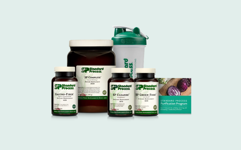 Supplements bottles and a shaker cup on a light background with a card that says "Standard Process Purification Program."