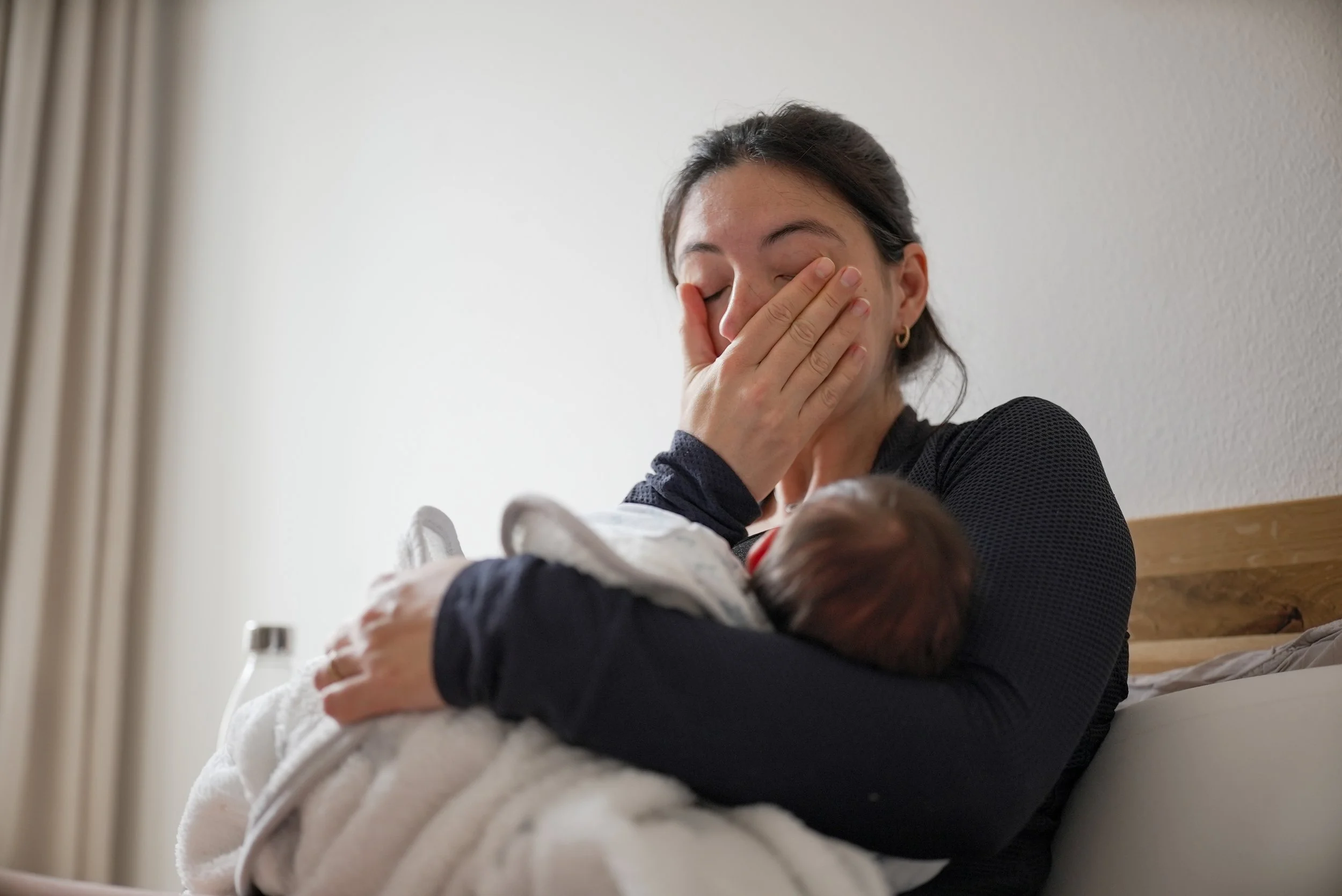Mother breastfeeding her newborn while adjusting her latch for a more comfortable feeding