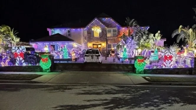 A house decorated with colorful Christmas lights and inflatable decorations at night.