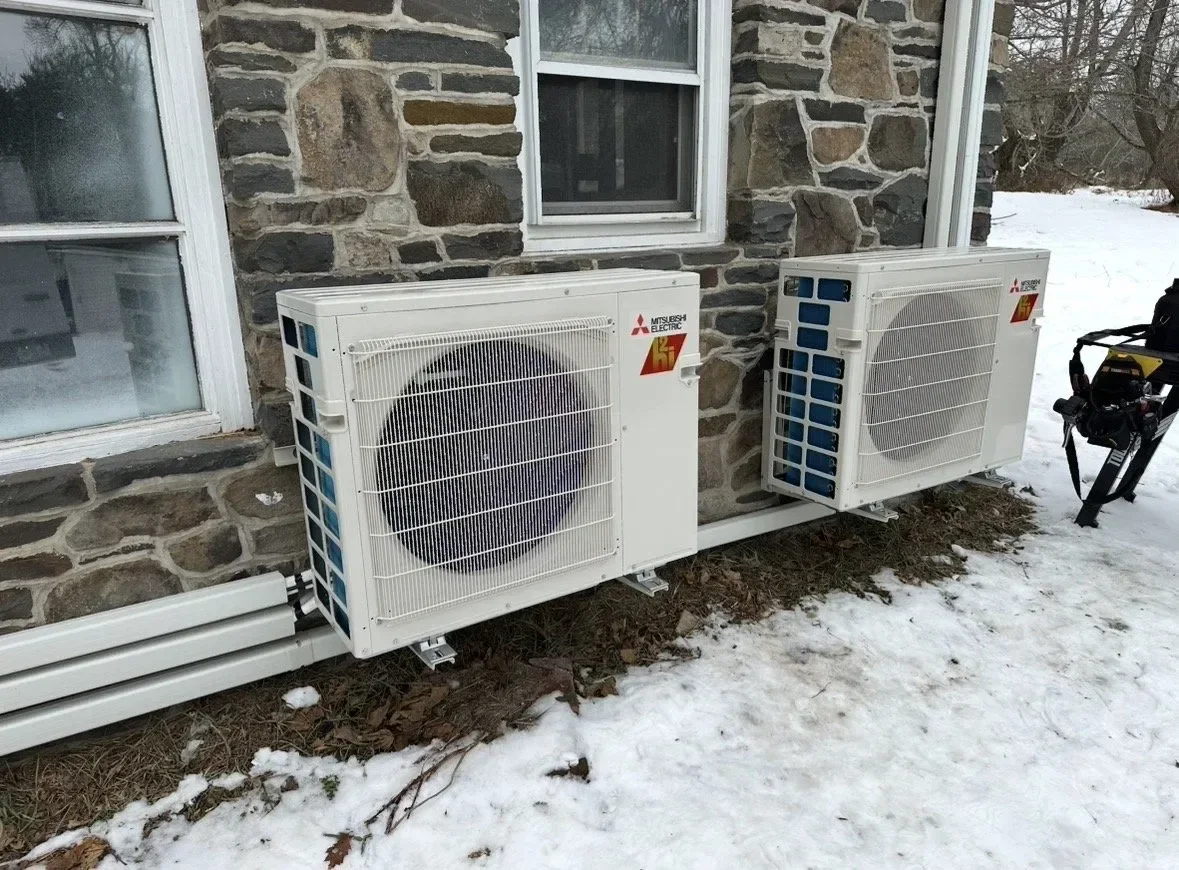 Two Mitsubishi Electric mini-split condensers installed in winter on a stone home in Ulster County NY by AeroDrop