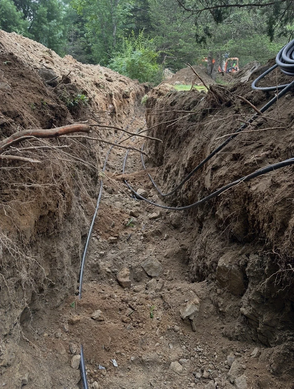 Excavated trench showing geothermal ground loop pipes being installed in Hudson Valley, NY