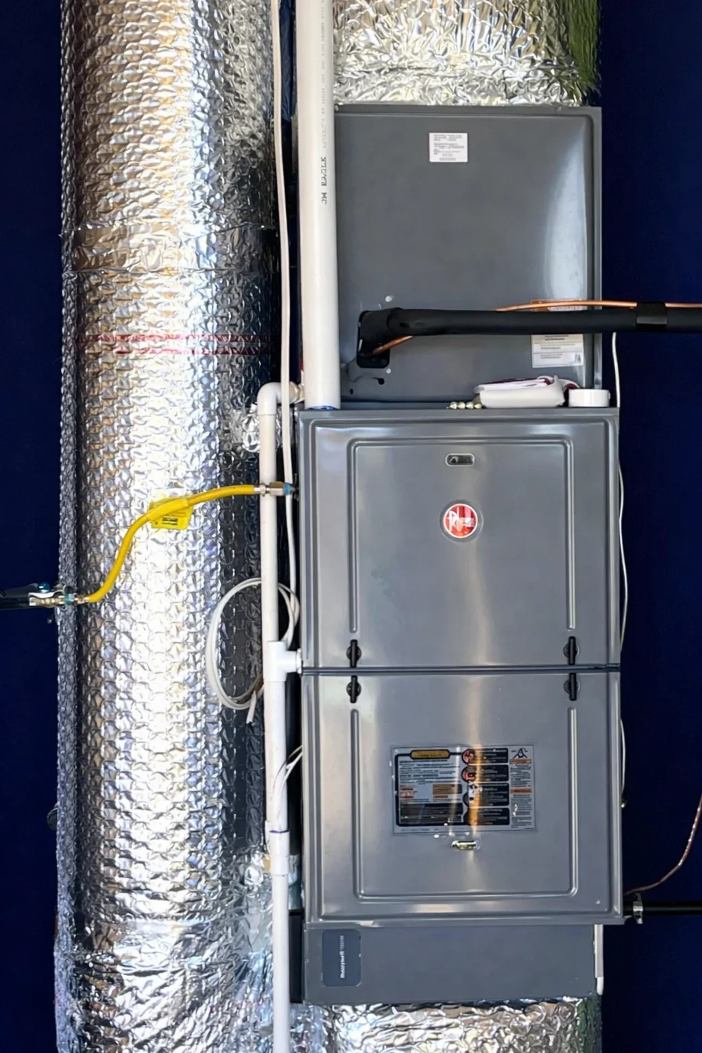 Rheem geothermal heat pump indoor unit installed with insulated ductwork and piping connections