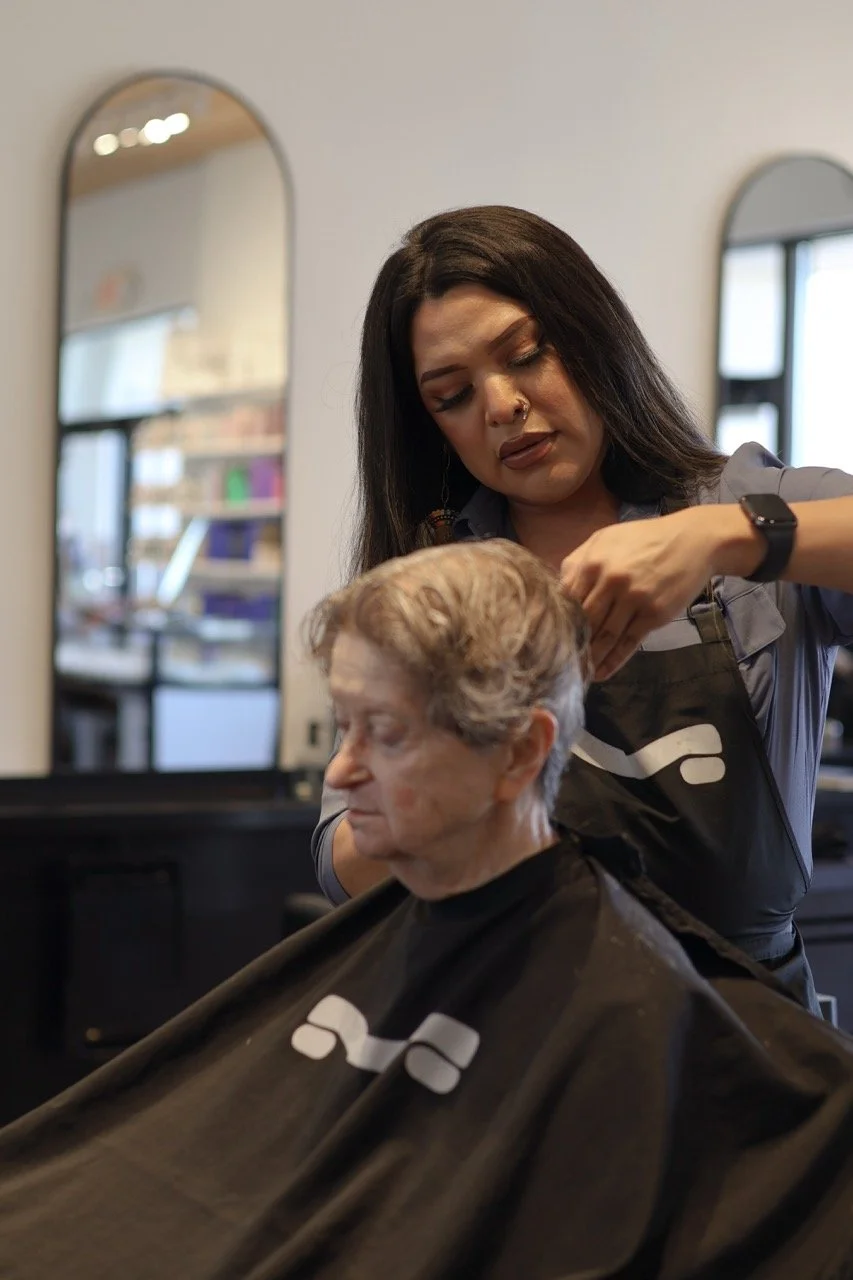 A woman is giving a haircut to an elderly woman in a salon.