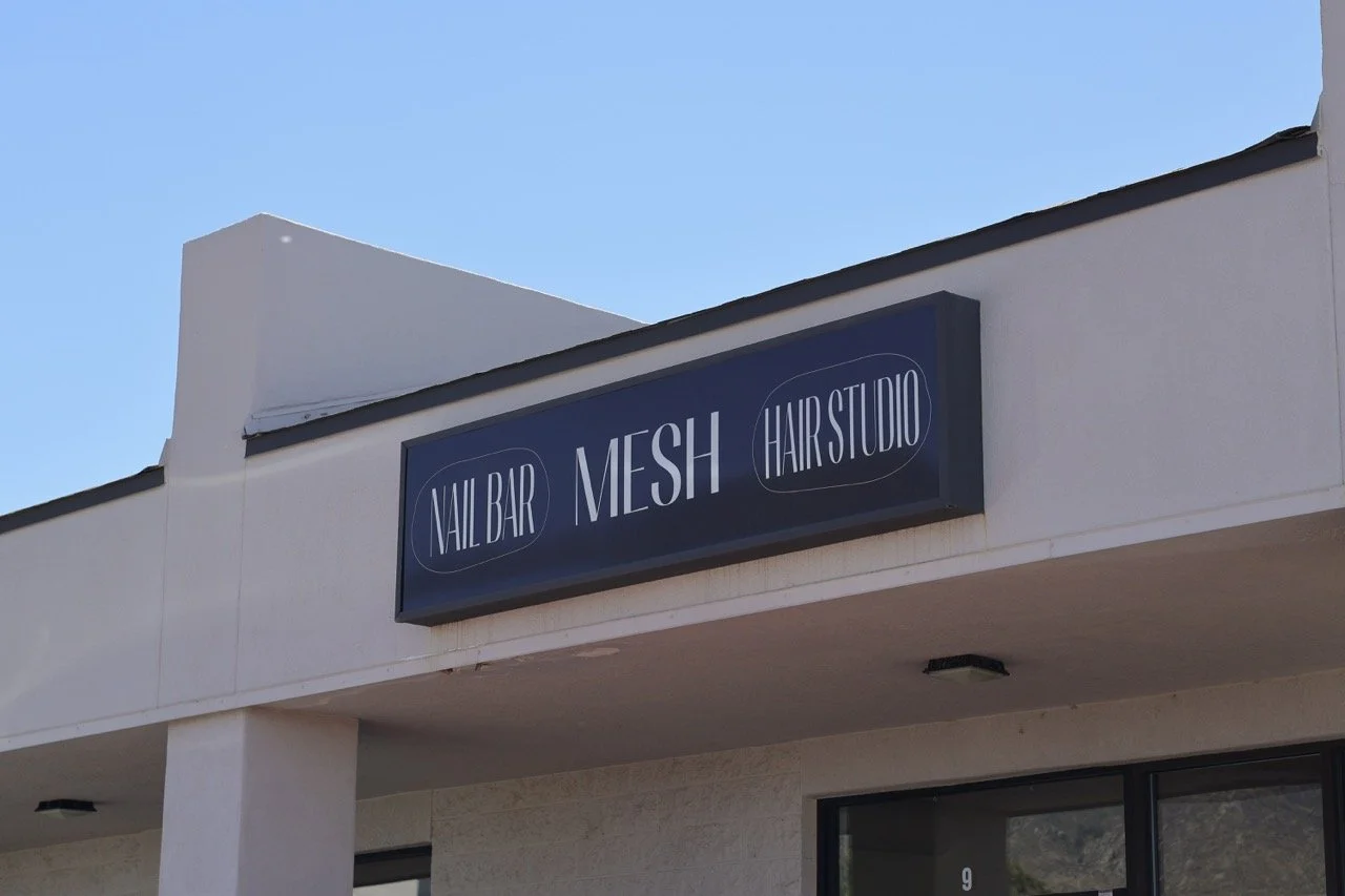 Business sign with white text on a navy background that reads 'Nail Bar, Mesh, Hair Studio'.