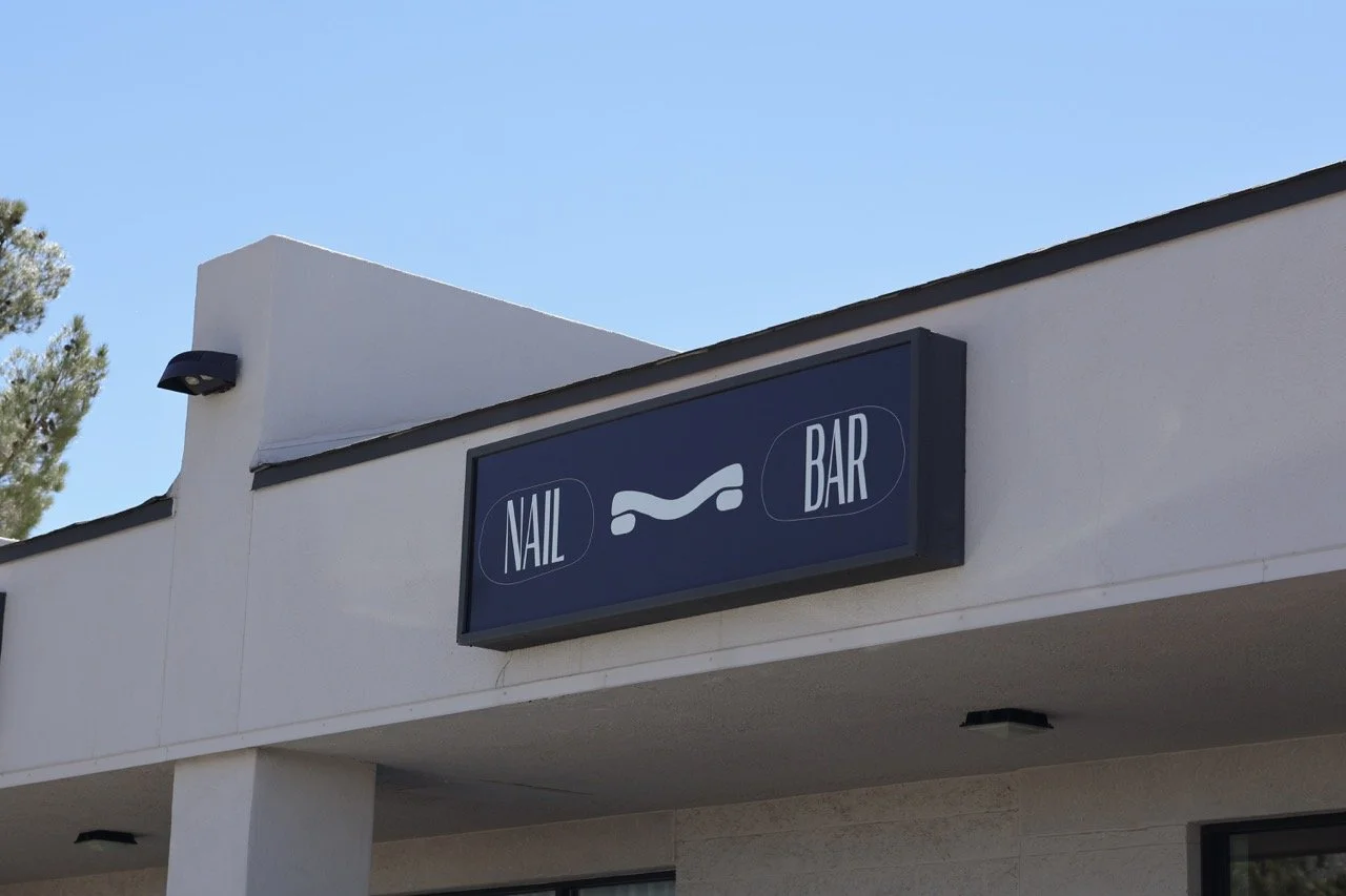 Sign for a nail and bar salon with icons of a nail and a wrench.