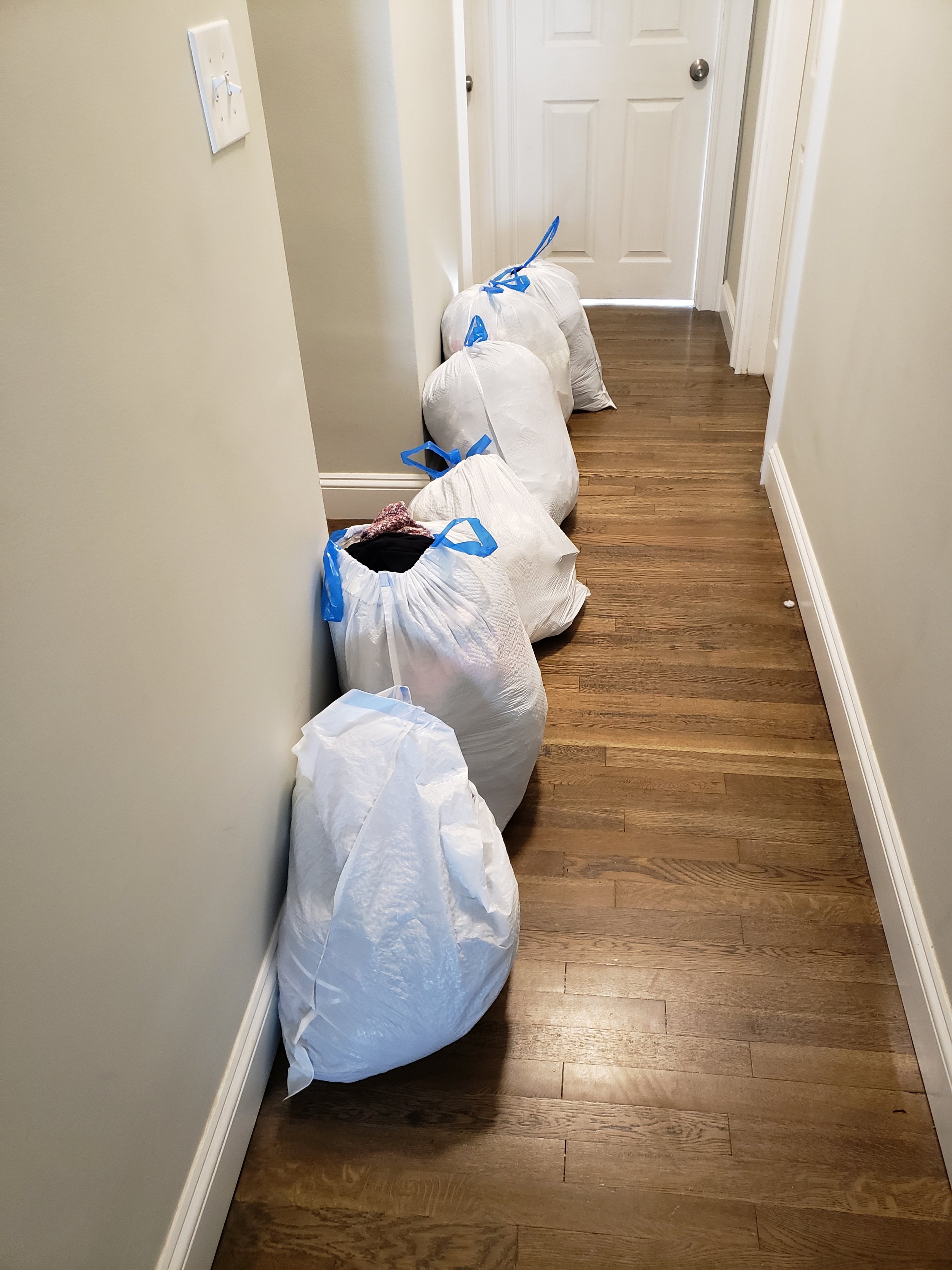 Hallway lined with six trash bags full of donation clothing
