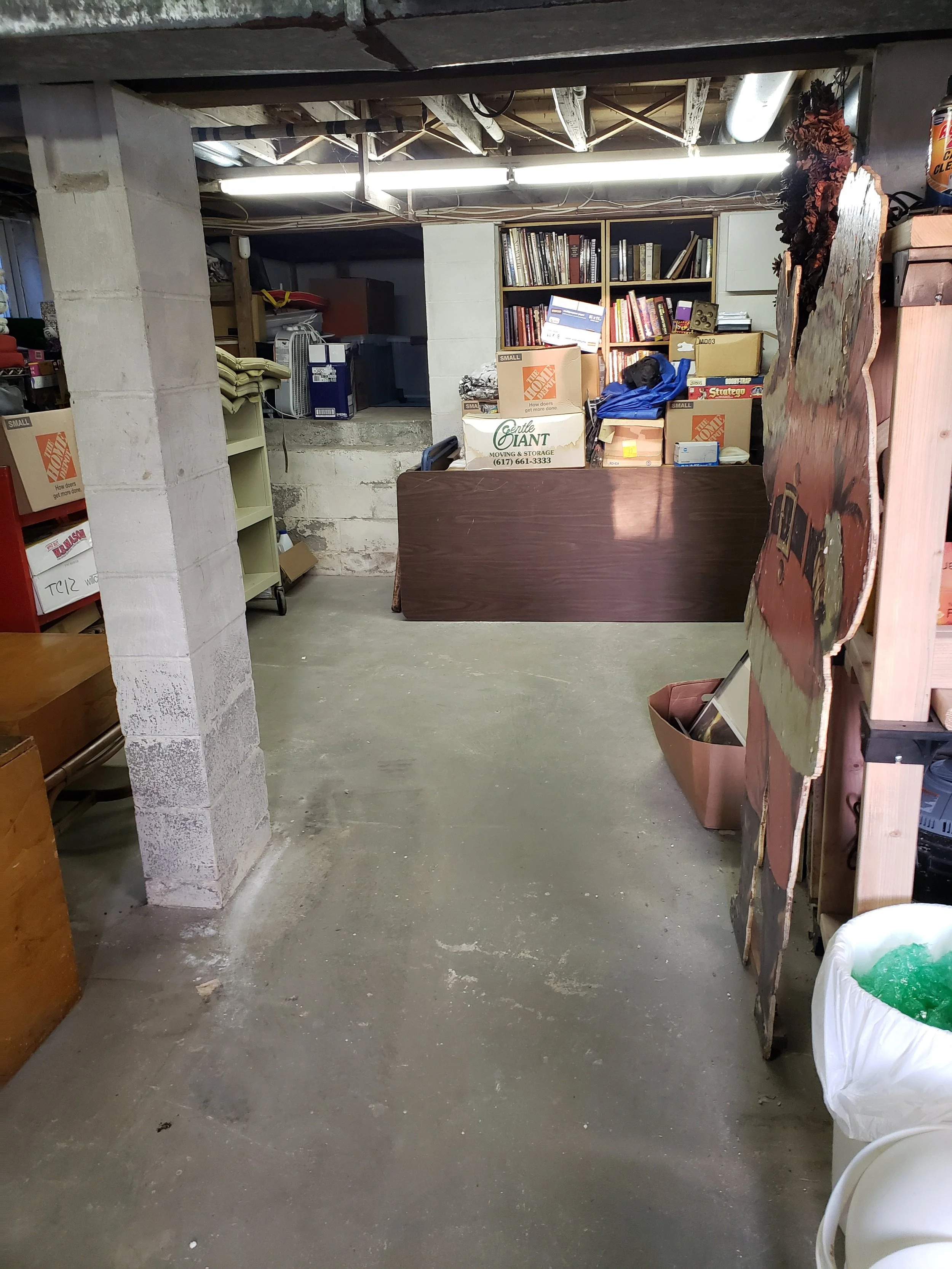 Basement with lots of floor space. Most miscellany has been cleared from the floor though some storage around the edges of the room remains.