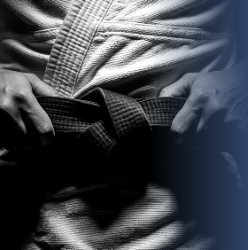 Close-up of a person adjusting a martial arts belt while wearing a gi.