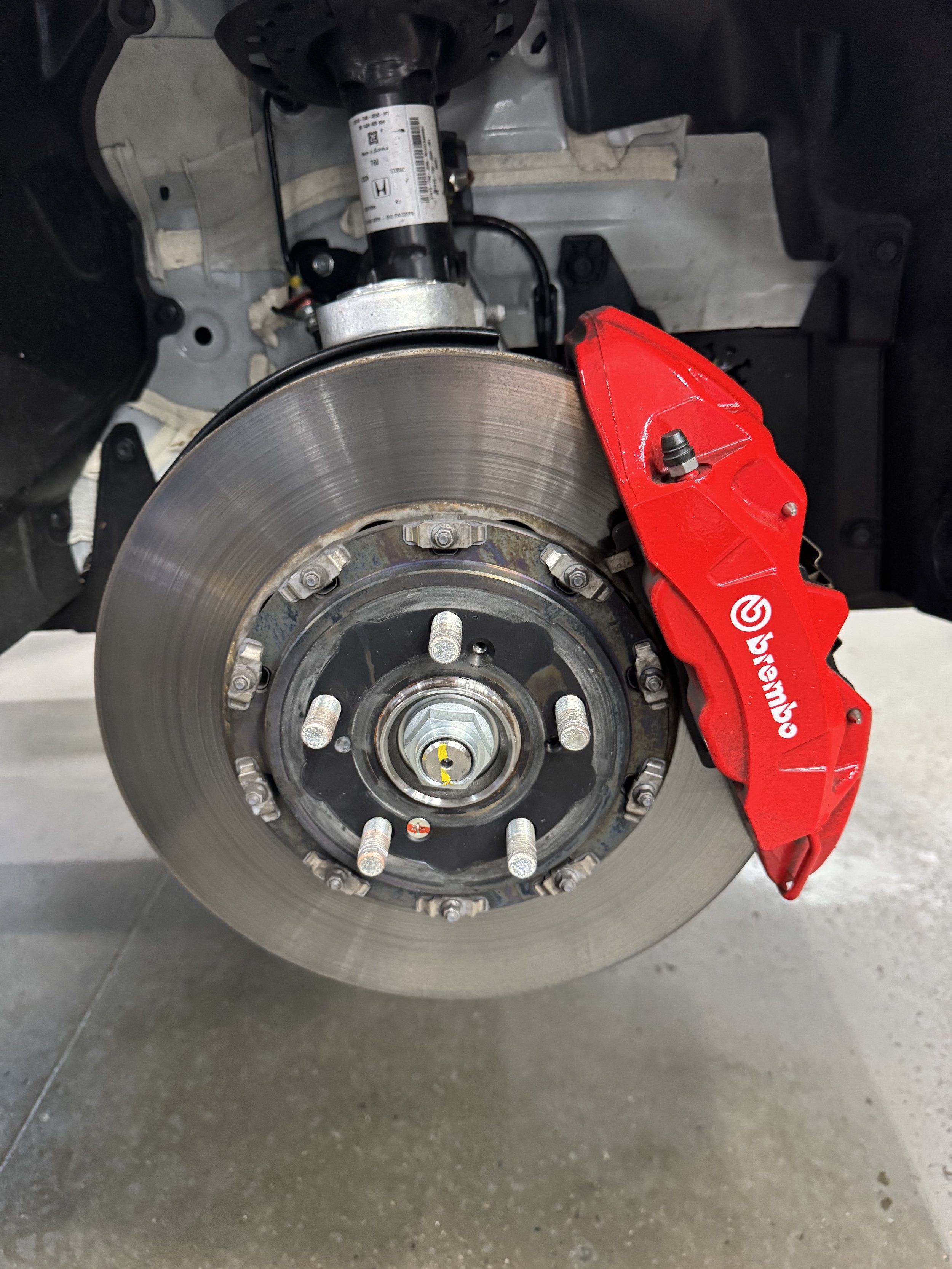 Close-up of a car's brake disc and red caliper with Brembo branding.