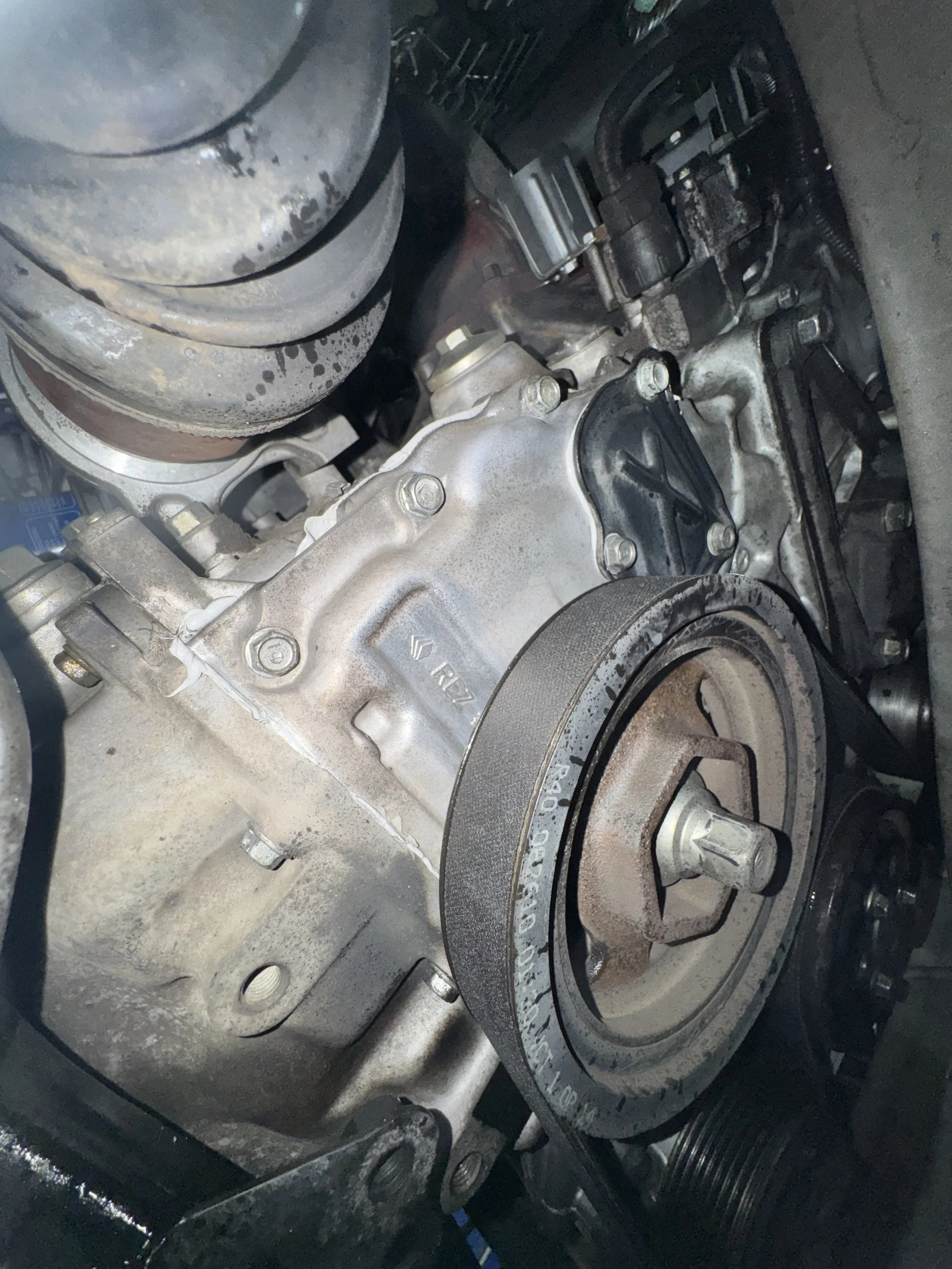 Close-up view of a car engine with a visible timing belt and pulley system.
