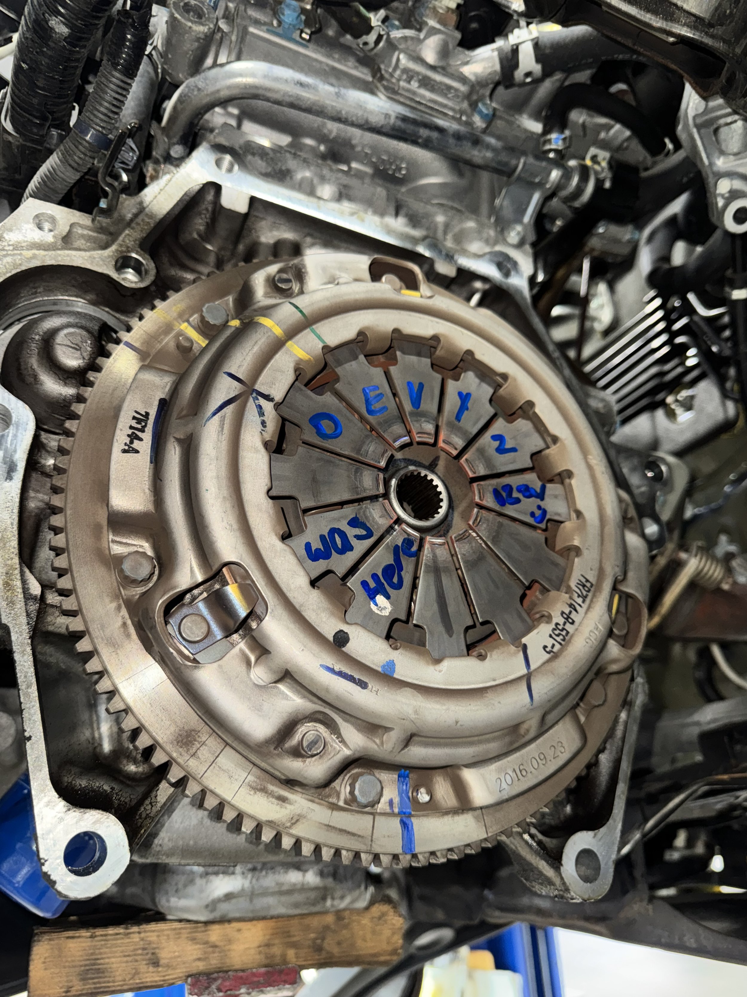 Automobile engine with handwritten notes marking different parts, including a clutch assembly and various colored lines and labels.