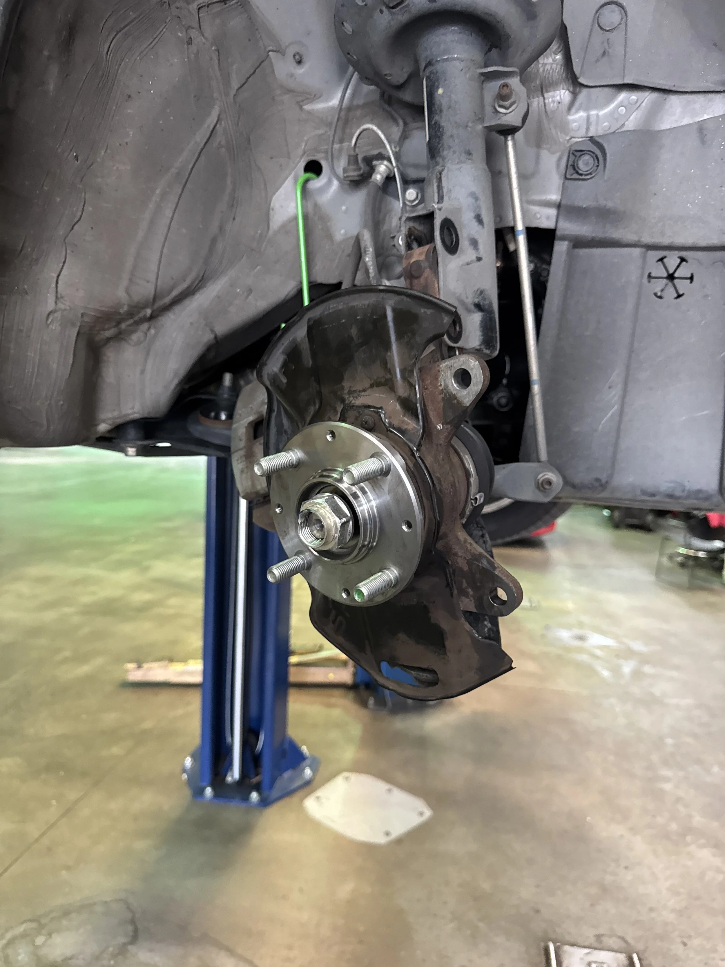 Car's front hub assembly and suspension components in an automotive repair shop.