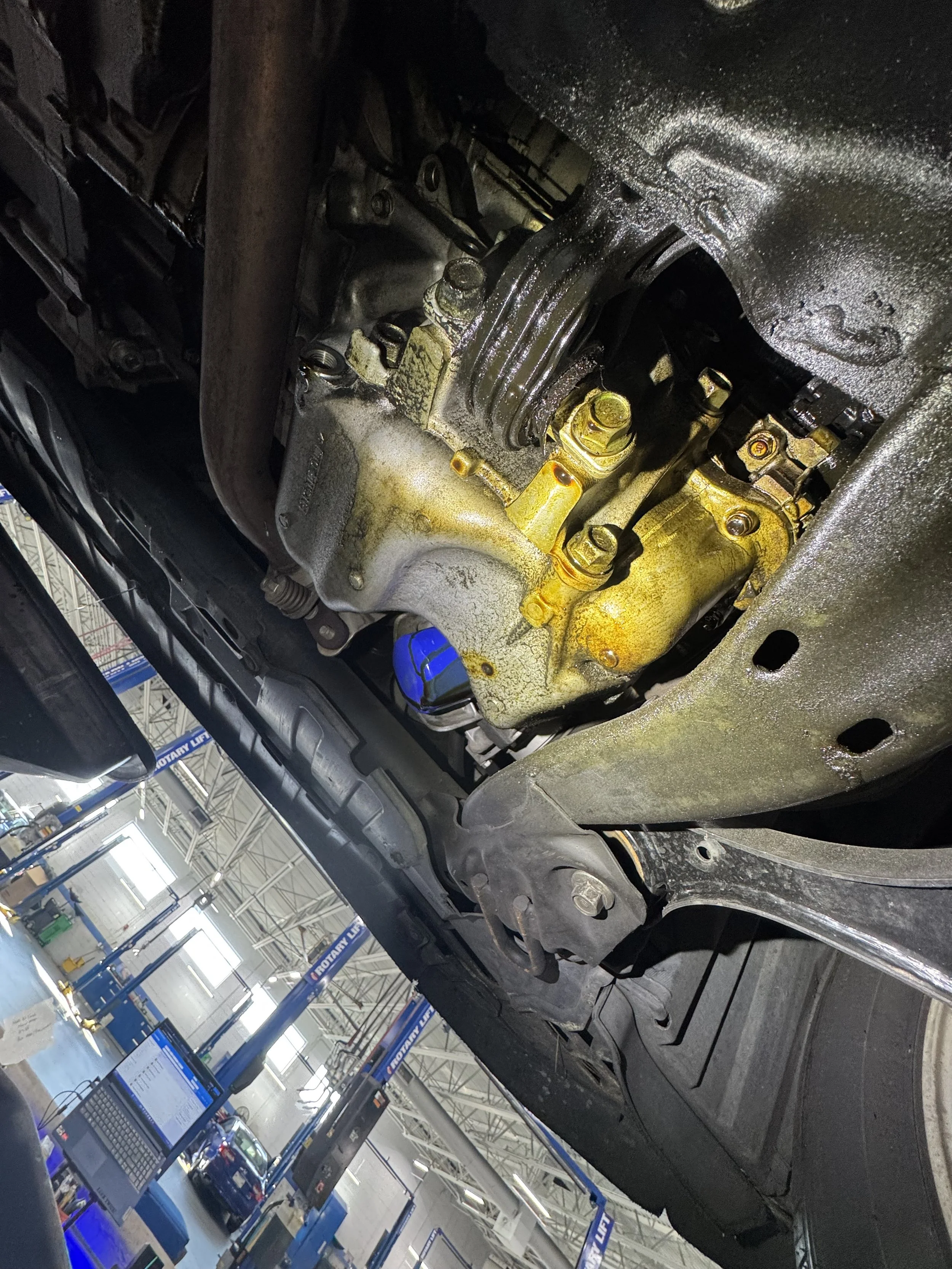 Underneath view of a vehicle's engine and chassis in an auto repair shop.