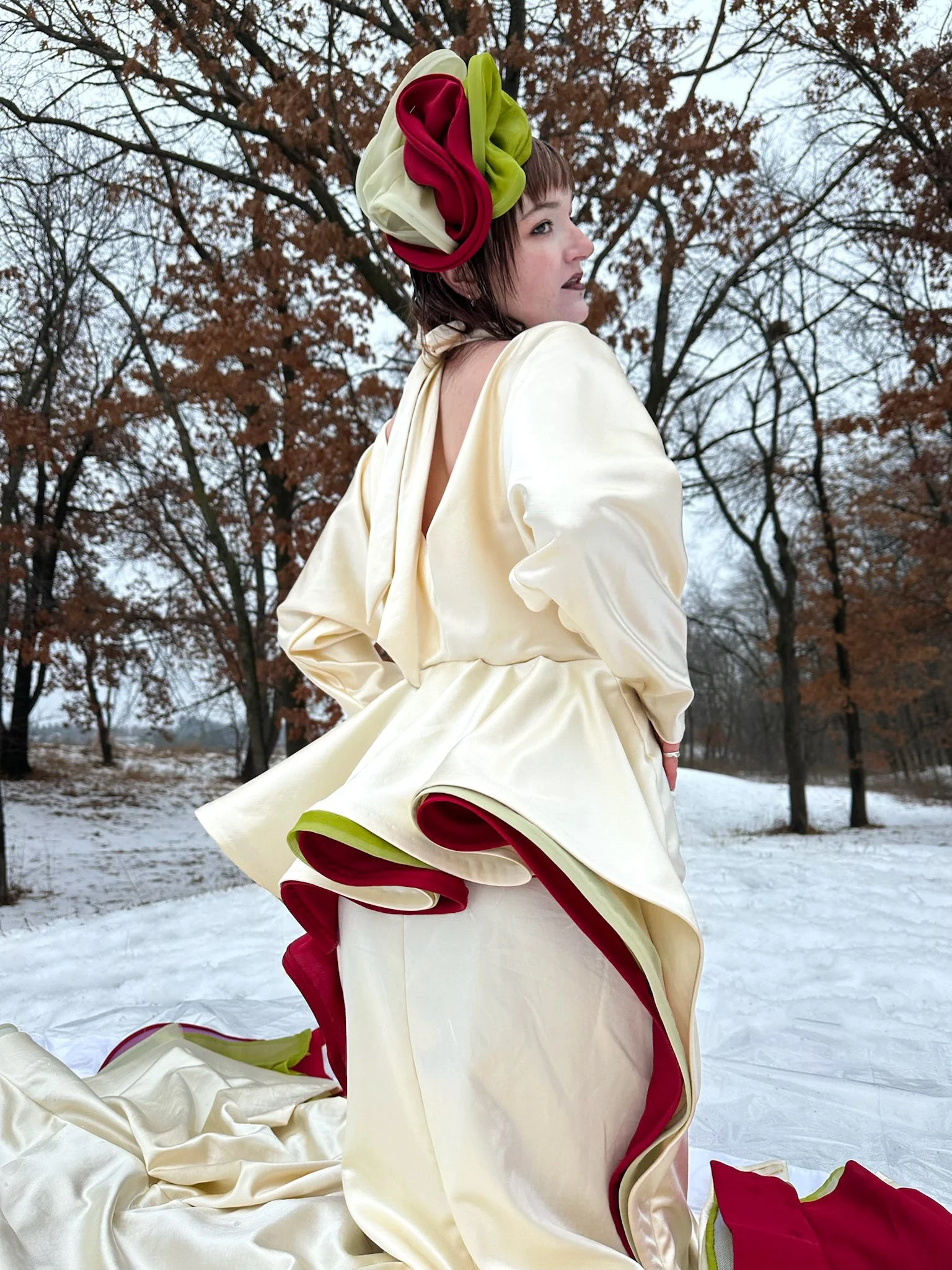 Bias cut dolman sleeve with a slight cowl v-neck drape at center back. Stylized half peplum at waist in back, full length trumpet shaped skirt, 3” horsehair hem, with invisible zipper underarm at left side seam.