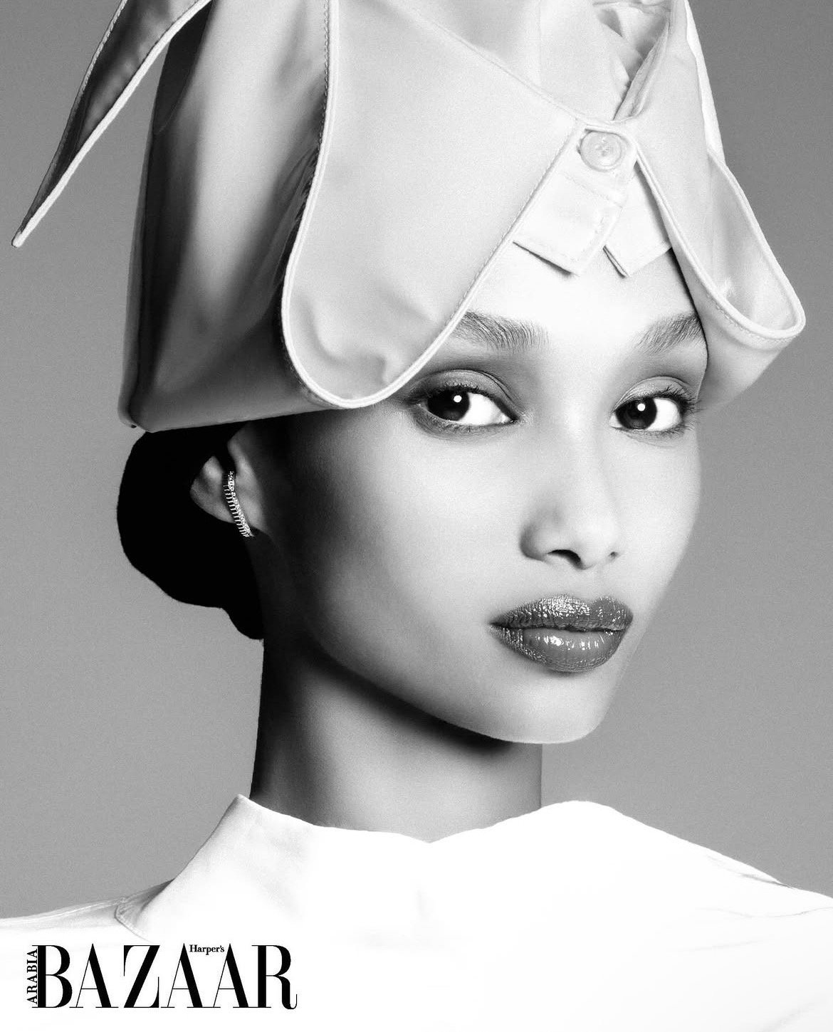 Black and white cover photo of a woman with styled hair and makeup wearing a large hat, with the words "Arabia Harper's Bazaar" at the bottom.
