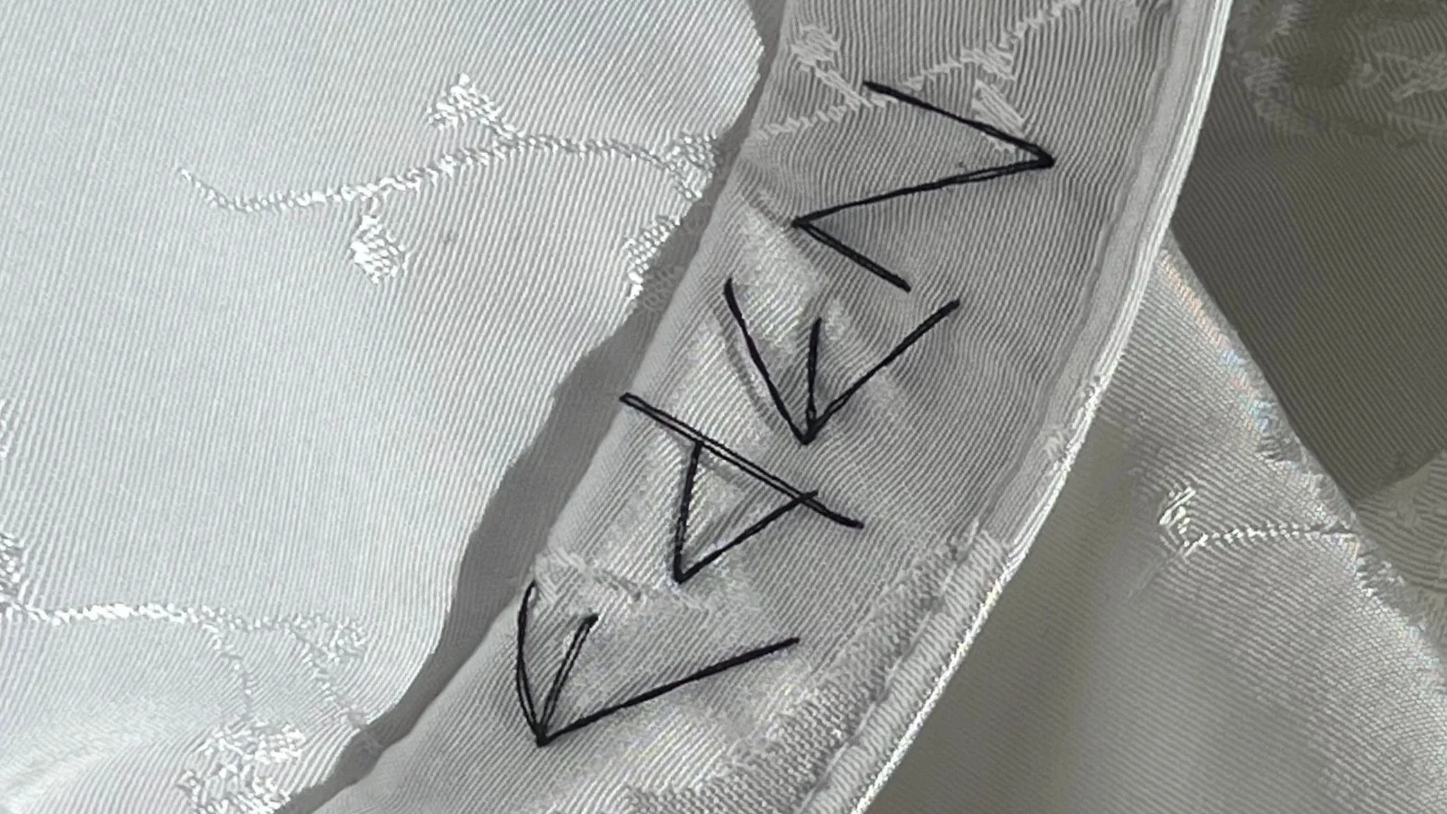 Close-up of a metallic surface with the word 'VAN' written in black marker, along with some shadows and reflections.