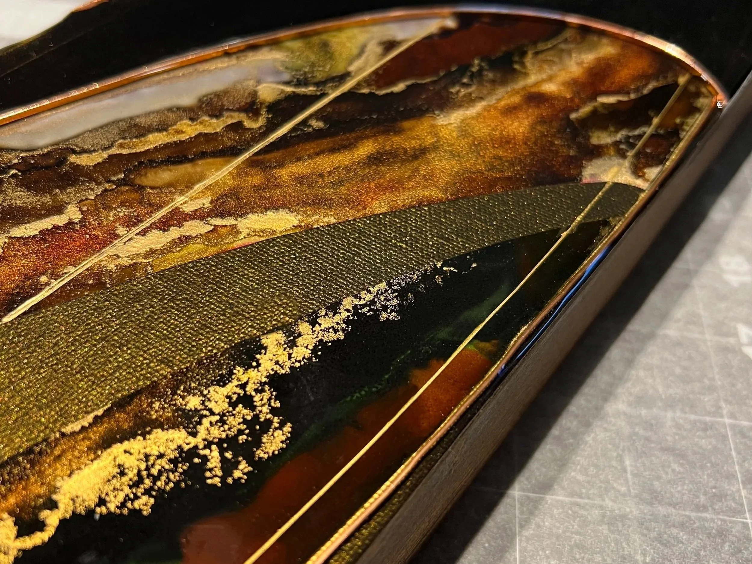 Close-up of art for sale showing wood edge frame with brown and gold colored textures below the acrylic surface.