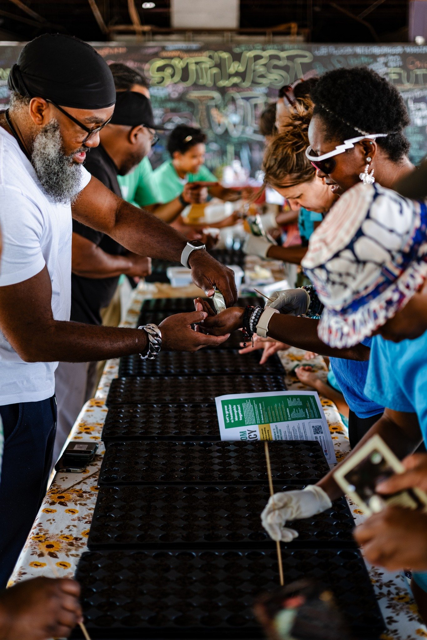 Attendees at one of Everbloom's seedling distributions at the Southwest Twin sow seeds to share with other community members.