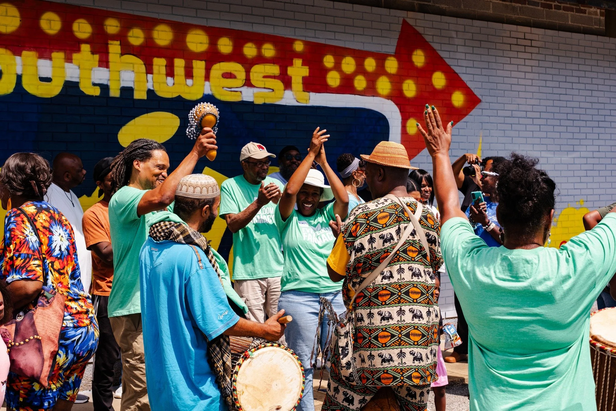 Attendees at one of Everbloom's Southwest Twin workshops and seedling distributions dance in front of the historic mural.