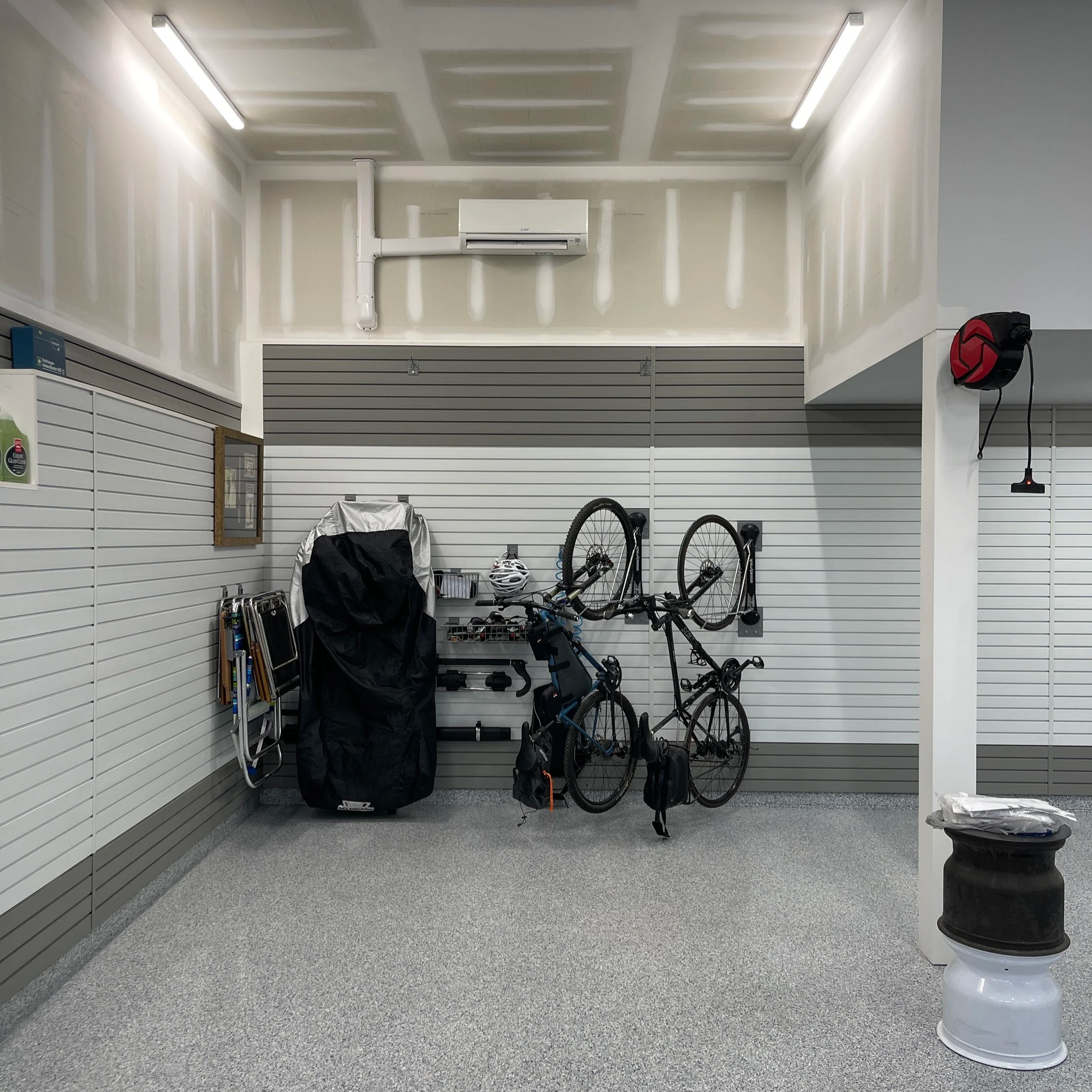 Empty store display with bicycles, a covered item, a skateboard, and helmets, with closed slat wall panels and fluorescent lighting.