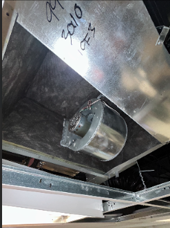 Close-up of an industrial or mechanical setting showing ductwork and a metal component, with handwritten notes on the metal surface, including the year 2010.