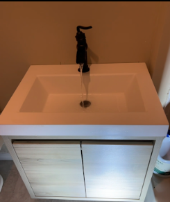 Modern bathroom sink with a black faucet and a white cabinet underneath.