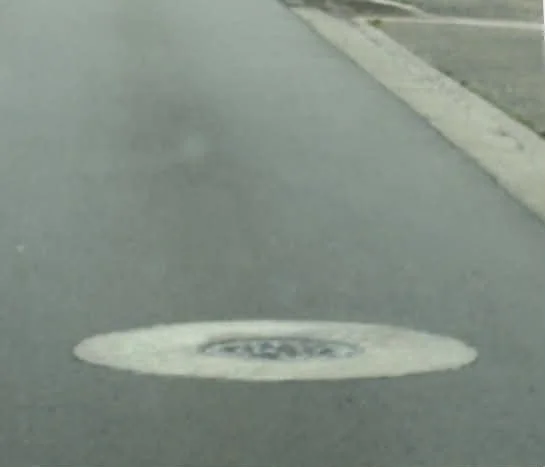 Close-up of a finished manhole cover on a paved road.