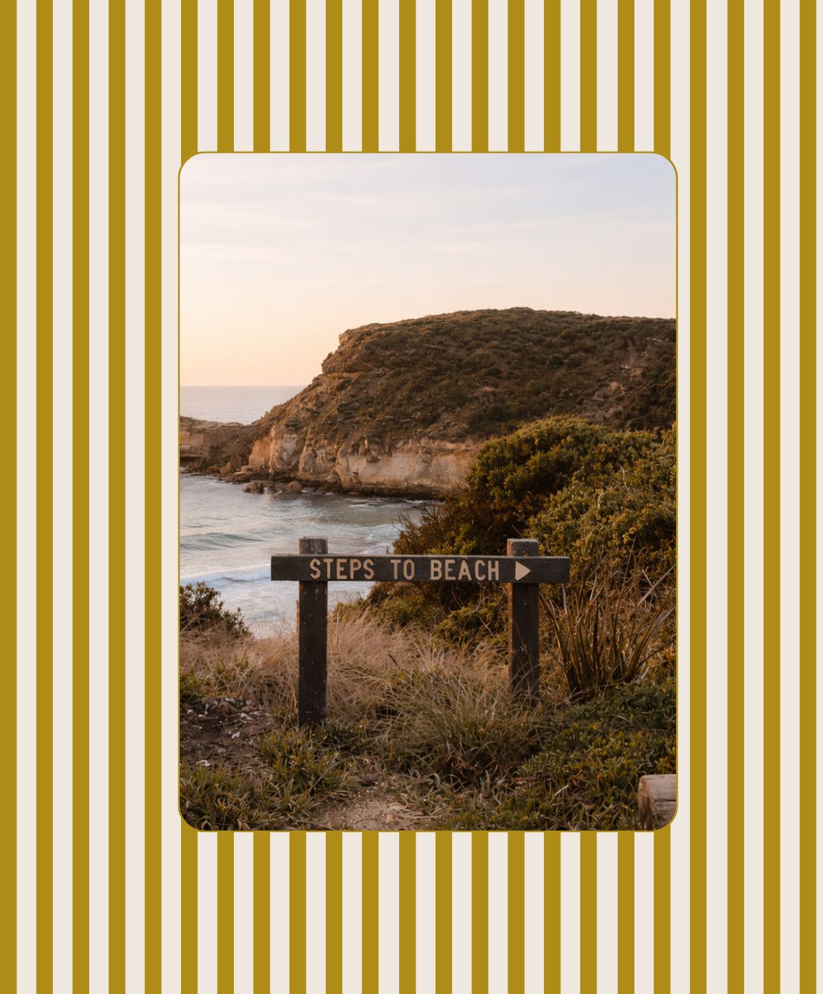 Sign reading 'Steps to Beach' pointing towards a coastal landscape with cliffs, ocean, and vegetation at sunset.