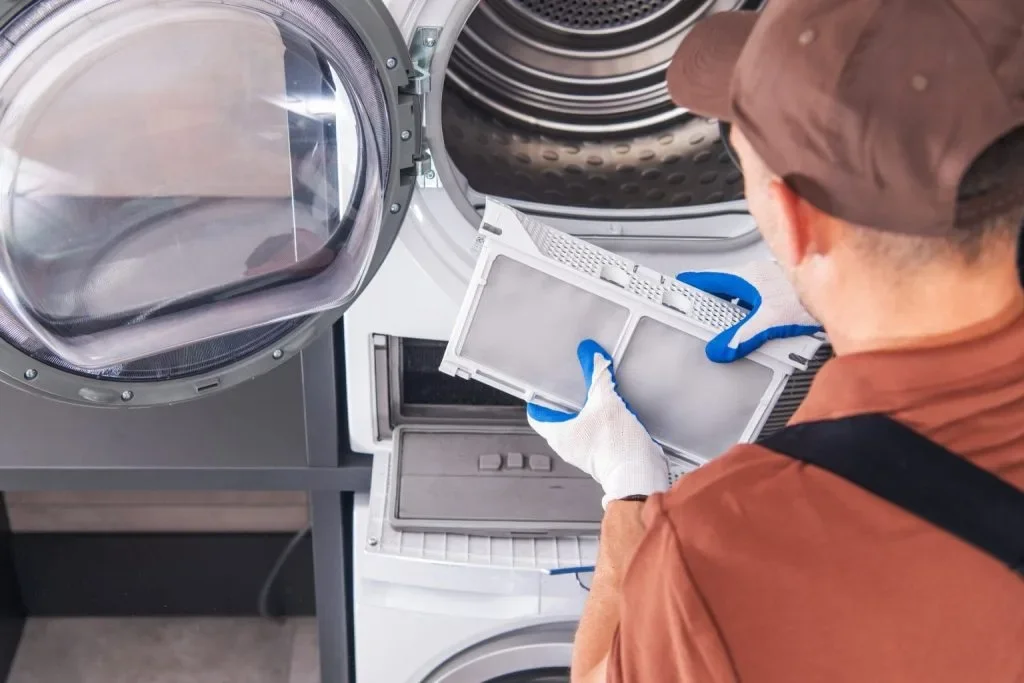 A person wearing gloves loading laundry into a washing machine in a laundromat.