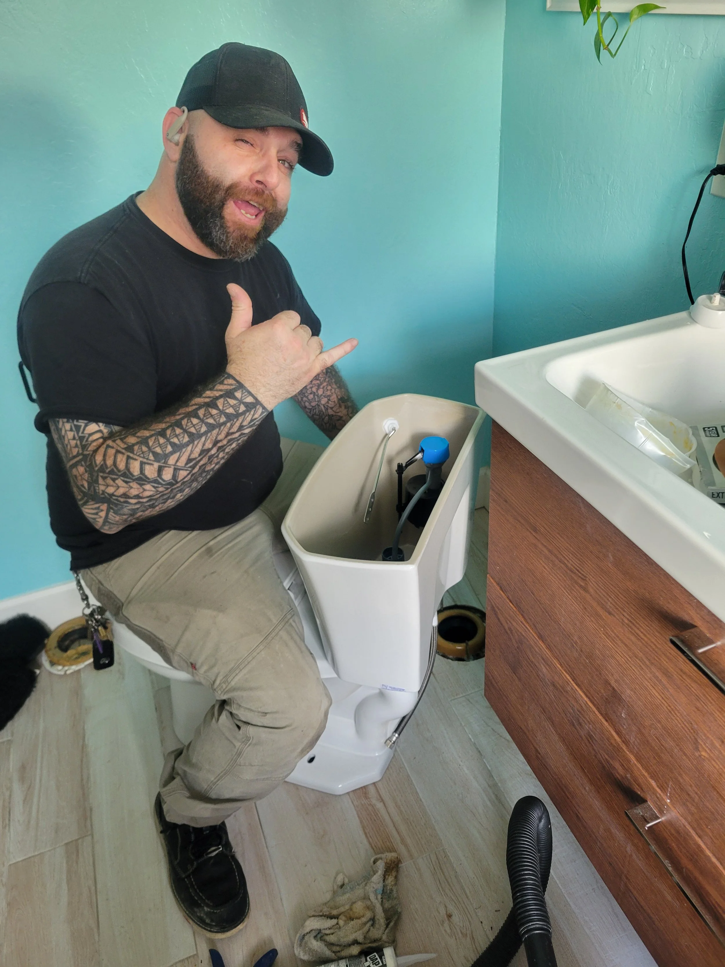 Daniel Davis of Emerald Systems repairing toilet tank components in residential bathroom, professional toilet repair service in East Bay