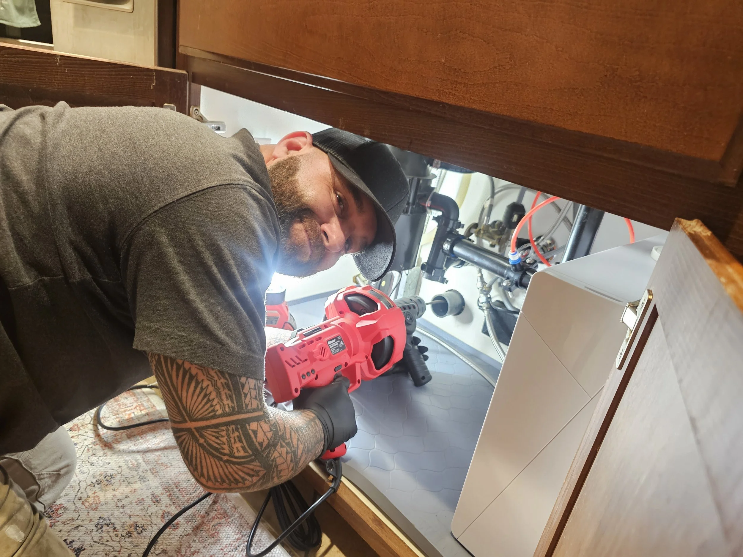 Daniel Davis of Emerald Systems clearing a clogged garbage disposal under kitchen sink, professional plumbing service in the East Bay area