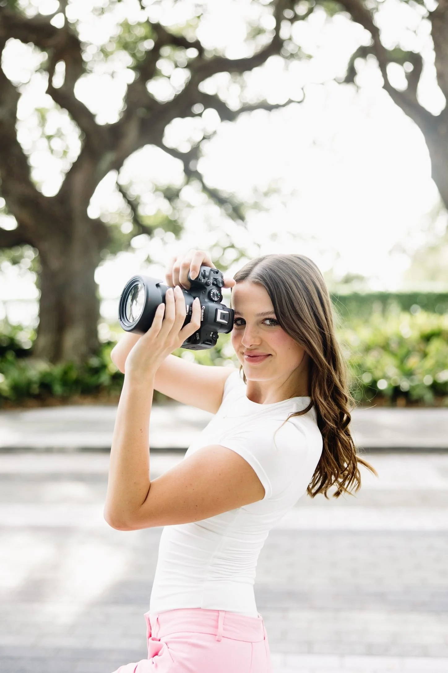 Young woman with brown hair using a camera outdoors.