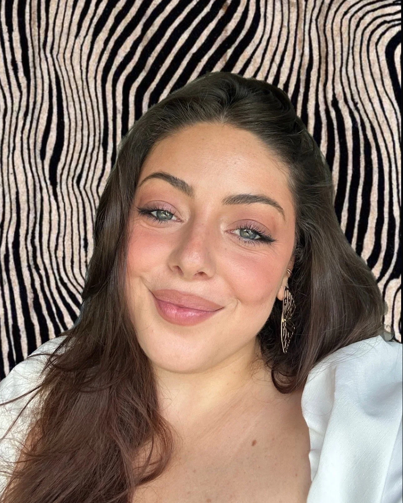 An image of Nessuna smiling in a white dress with a zebra print background