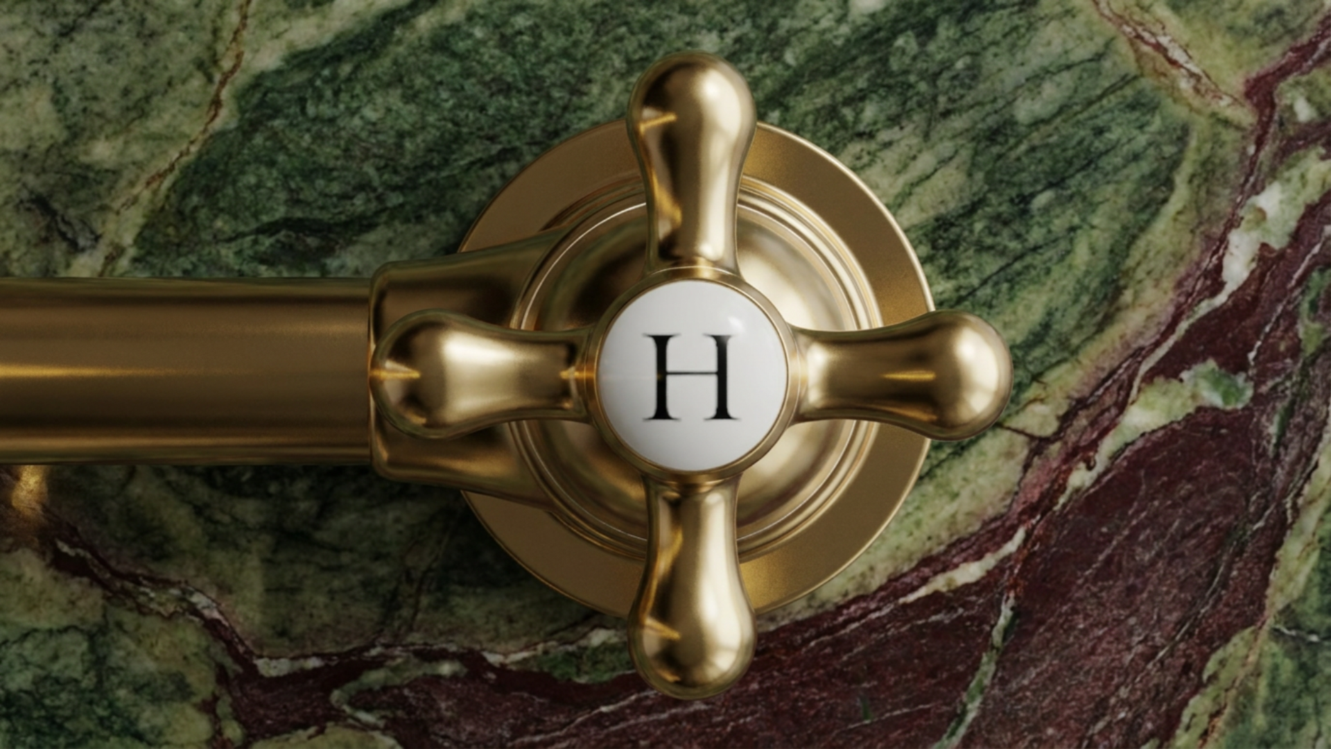 Close-up of a gold-colored faucet handle with a white circular center displaying the letter 'H,' mounted on a green and reddish marble countertop.
