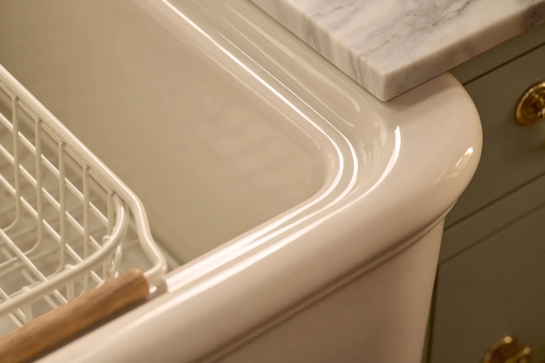Close-up of a kitchen countertop next to a sink with a dish rack, adjacent to a dishwasher with a white front and a marble countertop.