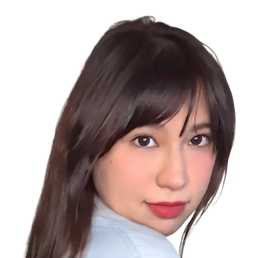 Close-up portrait of a young woman with long, brown hair and fair skin, smiling at the camera with a white background.