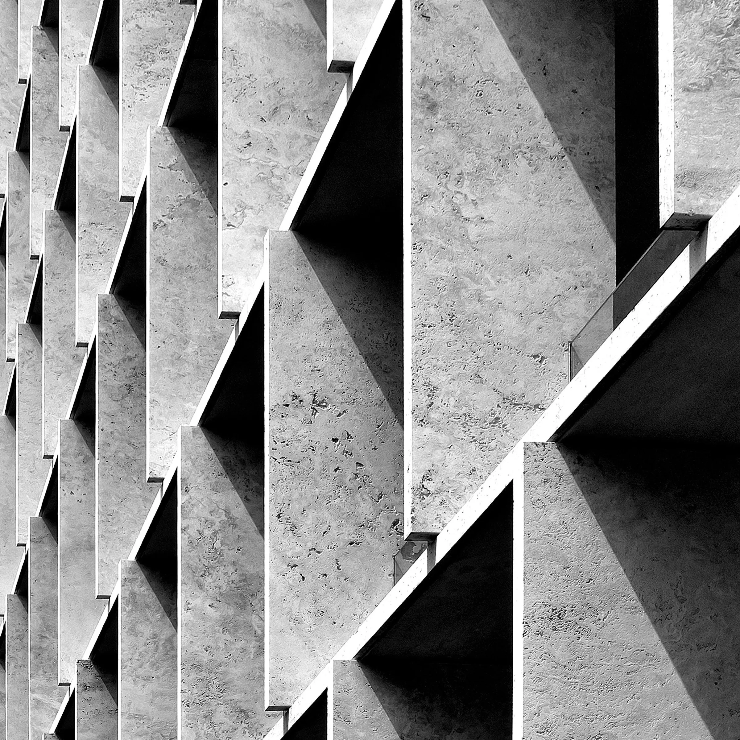 Fachada de edifício de concreto com janelas vazadas e sombras projetadas