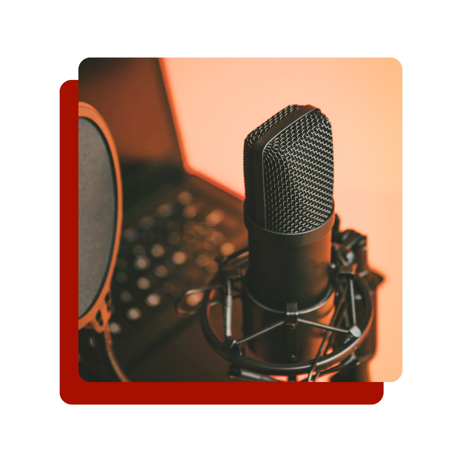 A close-up of a professional microphone mounted on a shock mount, with a blurred computer keyboard in the background, in a recording studio.