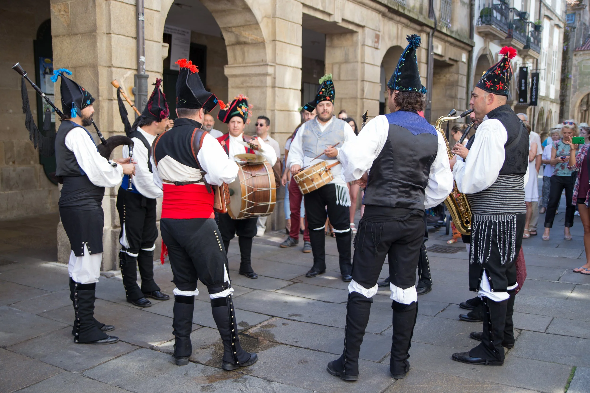 A group of traditional Galician bagpipers dressed in regional folk costume performing together in the Plaza do Obradoiro outside the Cathedral of Santiago de Compostela, Spain