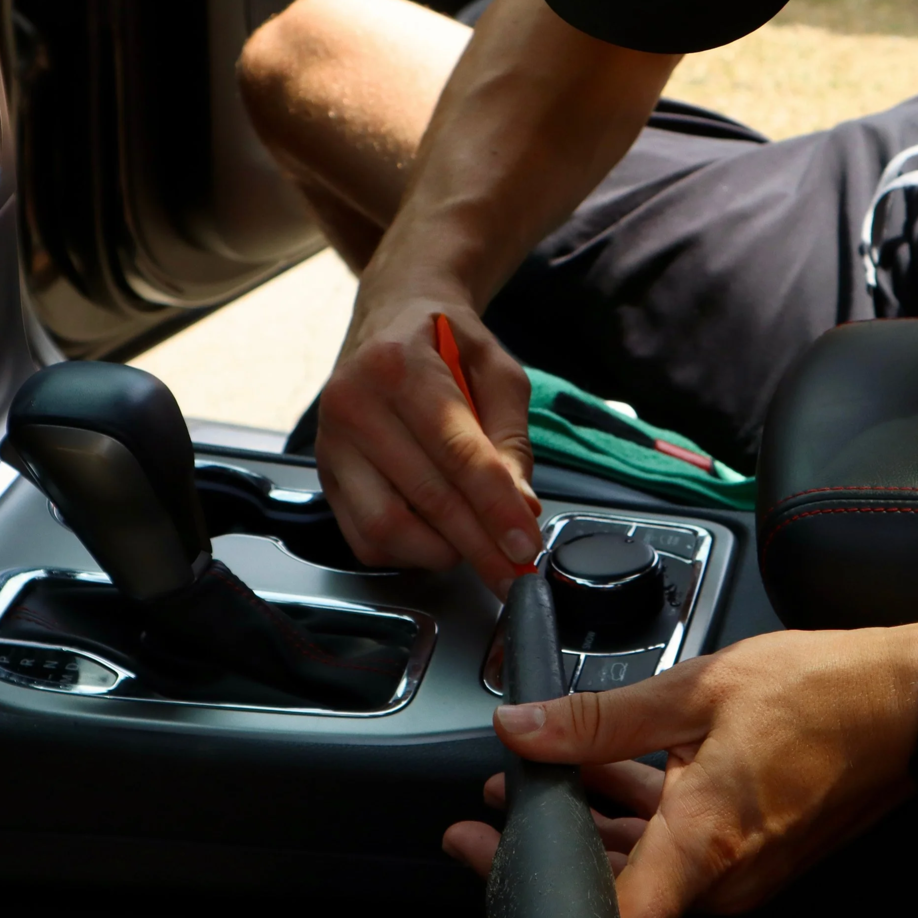 A person’s hands inserting a gear shift lever into a car's gear shift console.