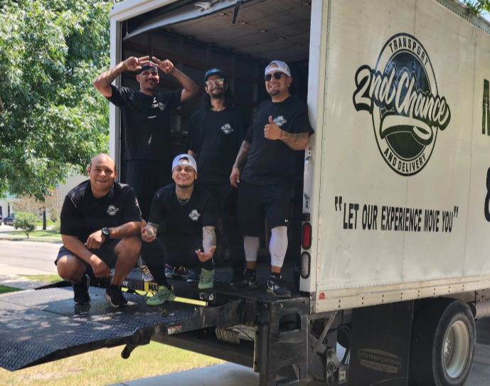 Five men posing inside and outside a moving truck, some making gestures and smiling, with a logo for '2nd Chance' and the slogan 'Let our experience move you' on the side of the truck.  The team that makes it happen.