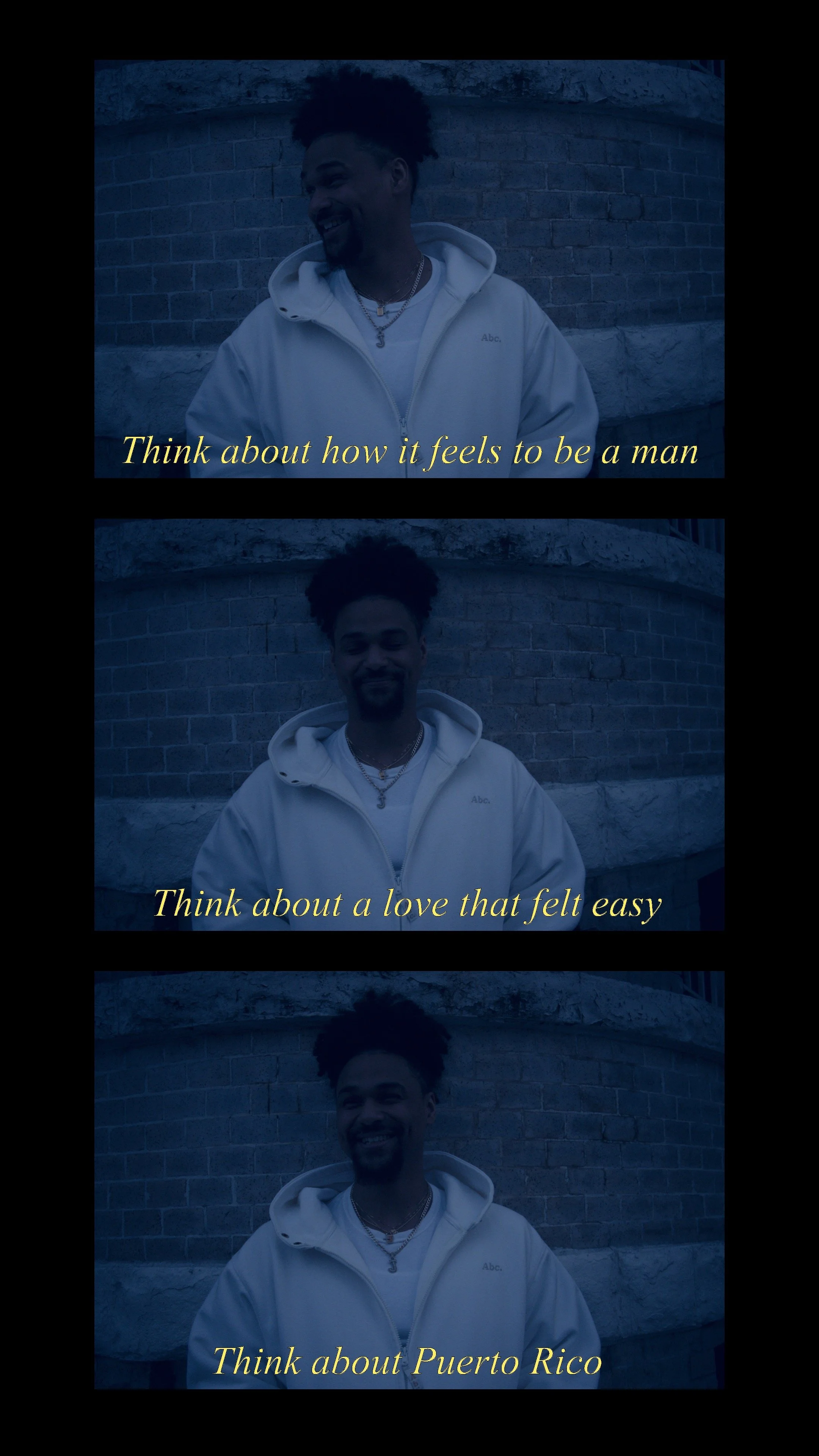 A young man with a beard and curly hair standing outside in front of a brick wall, wearing a white hoodie and smiling. The image is divided into three sections with yellow italicized text overlaid. The first section says, "Think about how it feels to be a man," the second says, "Think about a love that felt easy," and the third says, "Think about Puerto Rico."