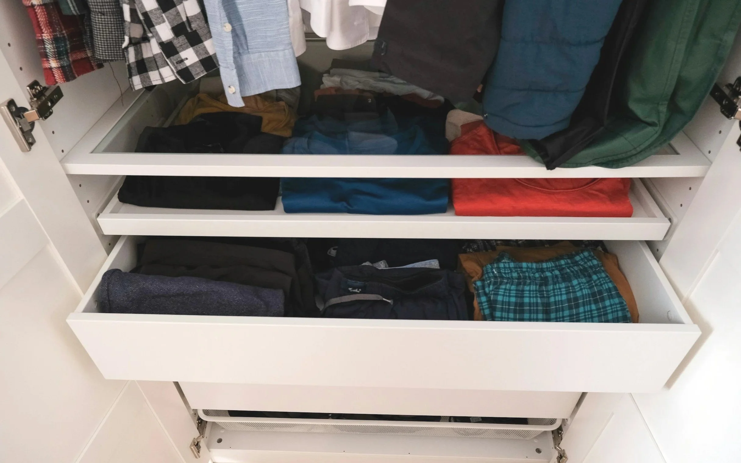 Open white closet with three shelves filled with folded clothes including shirts, jackets, and pants. West Hartford Closet Company WH Closet Co.