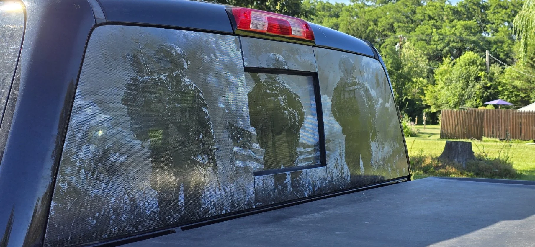 Reflection of three soldiers in the rear window of a vehicle.